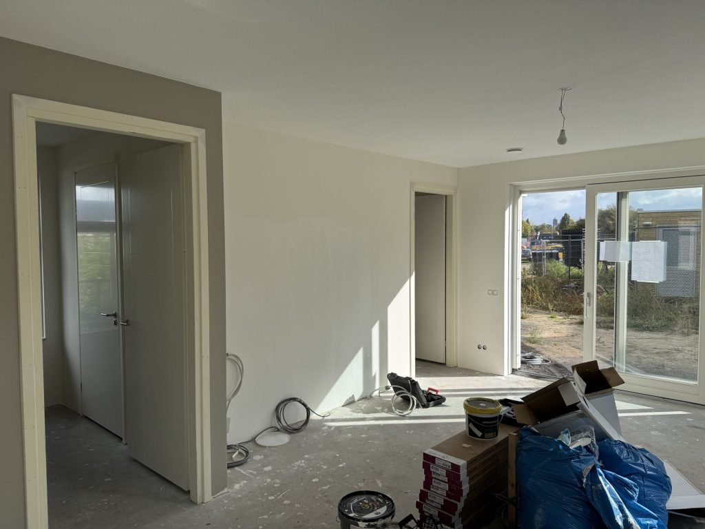 Nieuw appartement met pas afgewerkte wanden, binnendeuren en schuifpui naar een bouwterrein